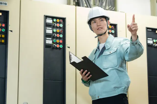分電盤の前で指差し確認をする男性施工管理技士