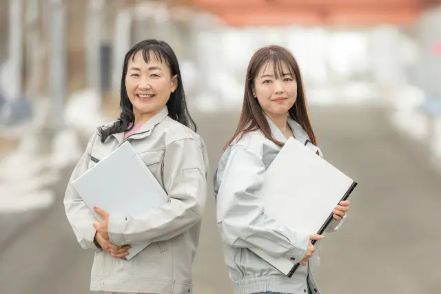 2人の女性施工管理技士が笑顔でこちらを向いている