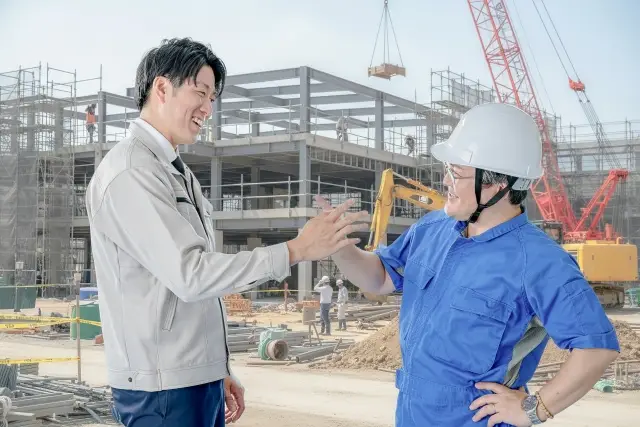 手を組む現場代理人と主任技術者