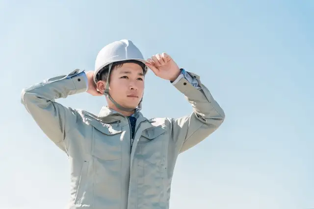 ヘルメットをかぶり直す作業員
